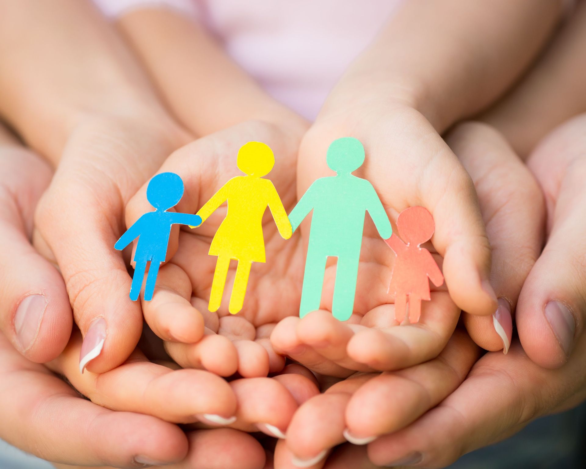 Schützende Hände legen sich zusammen um eine Familiendarstellung
