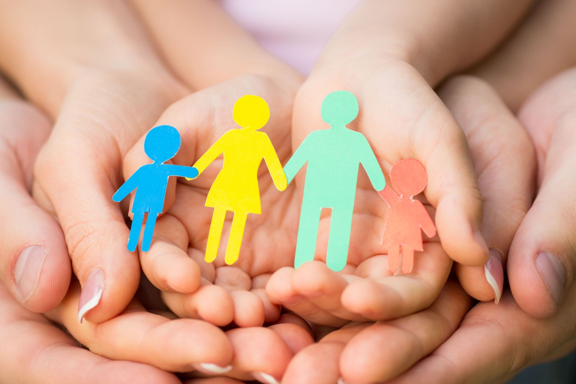 Schützende Hände legen sich zusammen um eine Familiendarstellung