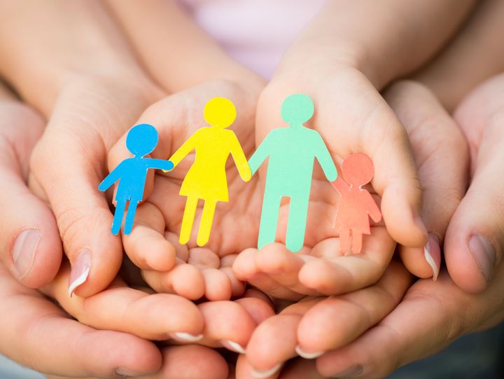 Schützende Hände legen sich zusammen um eine Familiendarstellung