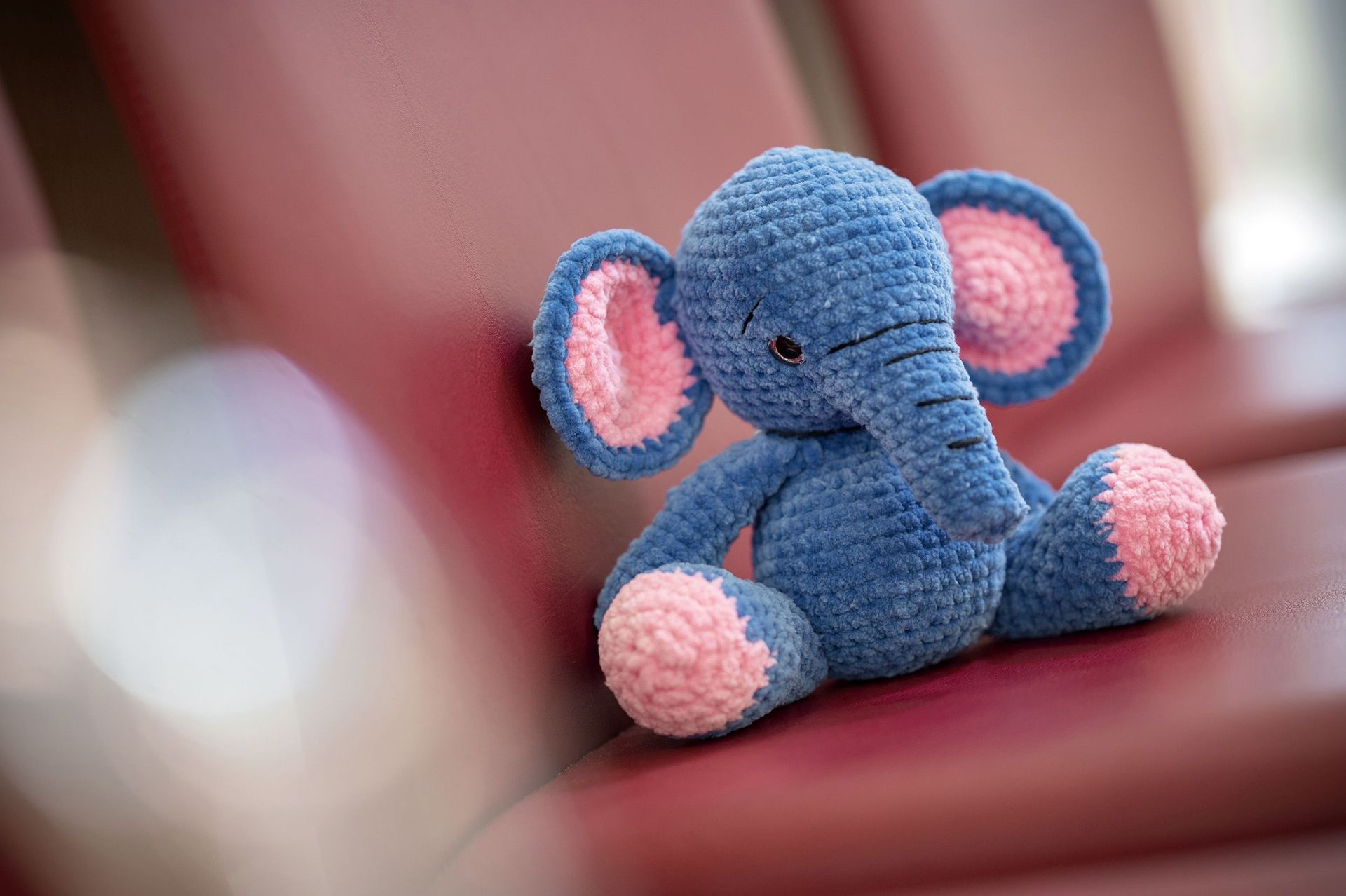 Kleiner Stofftier-Elefant sitzt auf einem roten Stuhl